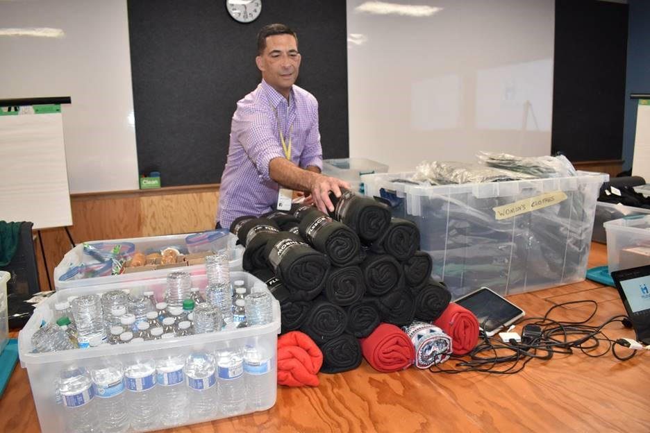 A man sitting in front of many rolls of black fabric.