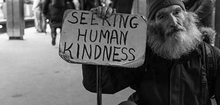 A man holding up a sign that says " seeking human kindness ".